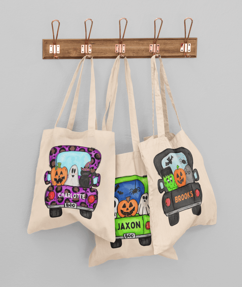 mockup of three customizable tote bags hanging against a solid color wall 41717 r el2